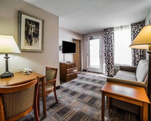 A hotel room with a desk, chair, sofa, television, and a patterned carpet. - MainStay Suites Casper (Casper)