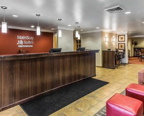 A hotel reception area with a wooden reception desk, a black carpet, and a tiled floor. - MainStay Suites Casper (Casper)