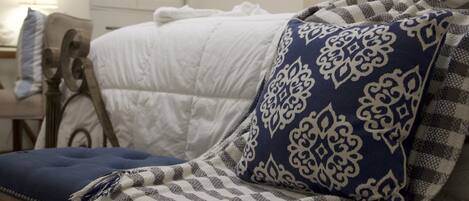 A bed with a white quilt and a blue and white patterned pillow.