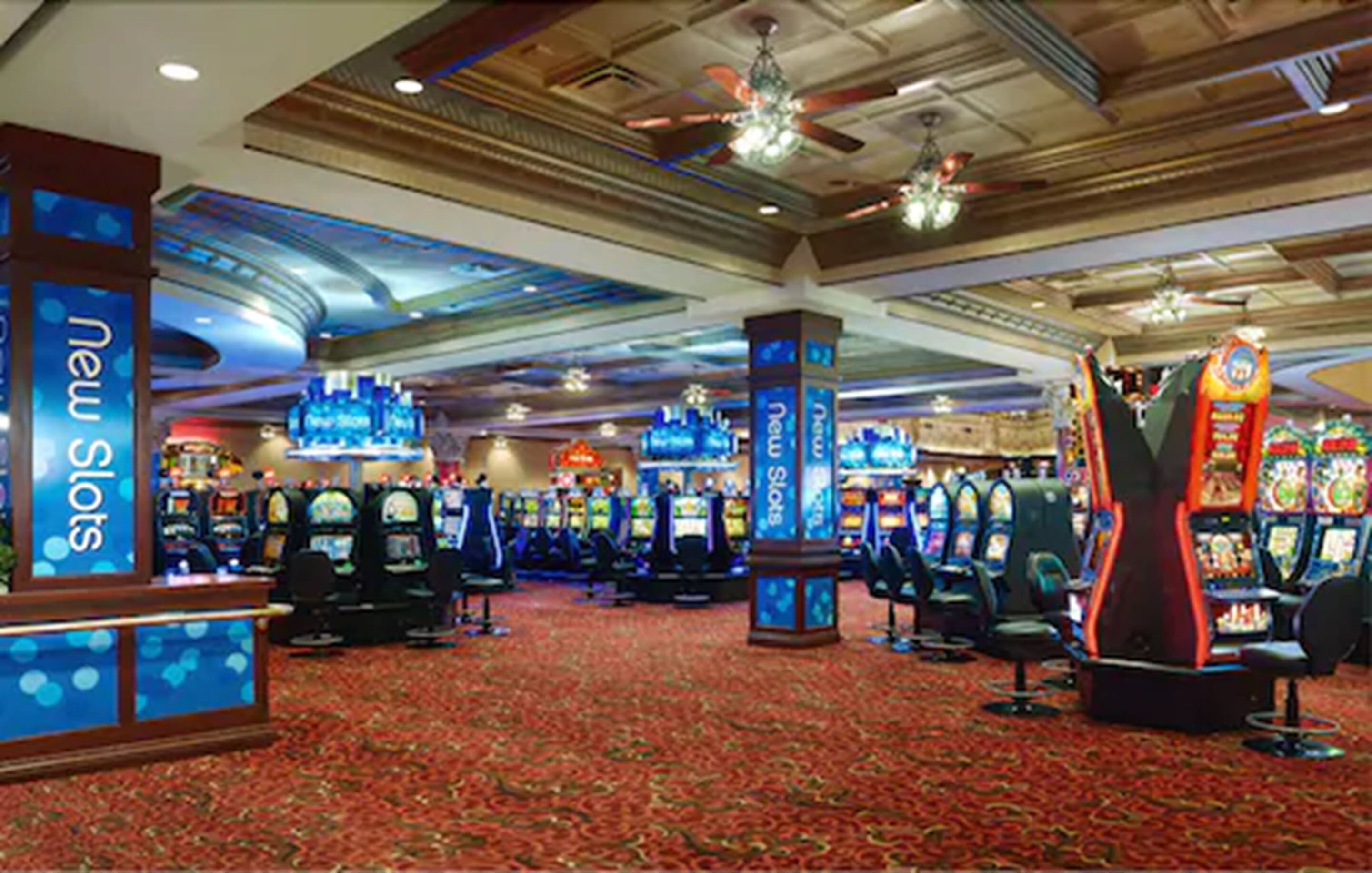 A casino with multiple slot machines and a carpeted floor.