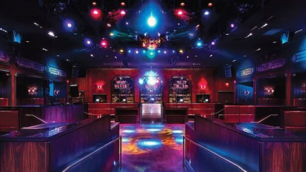 A bar with a neon-lit floor and a central stage.
