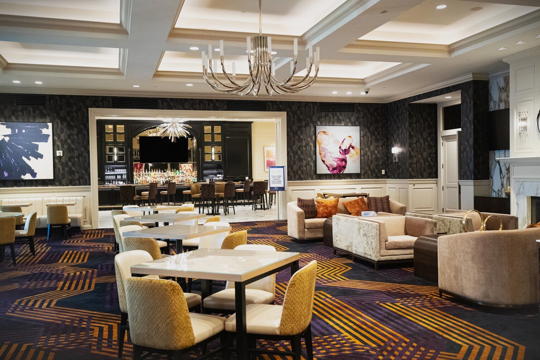 A hotel lobby with a bar area, seating arrangements, and a chandelier.