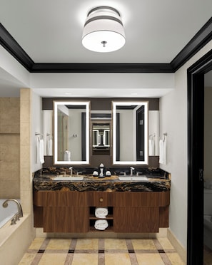 Un baño moderno con encimera de mármol, lavabos dobles y un espejo grande.
