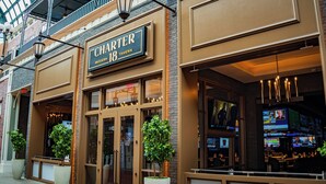 A modern tavern with a large sign, glass doors, and indoor seating visible through the windows.