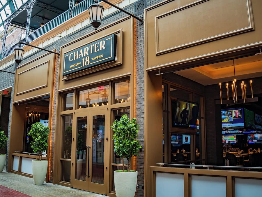 A modern tavern with a large sign, glass doors, and indoor seating visible through the windows.