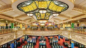 A grand lobby with a central chandelier, multiple levels, and rows of liquor bottles.