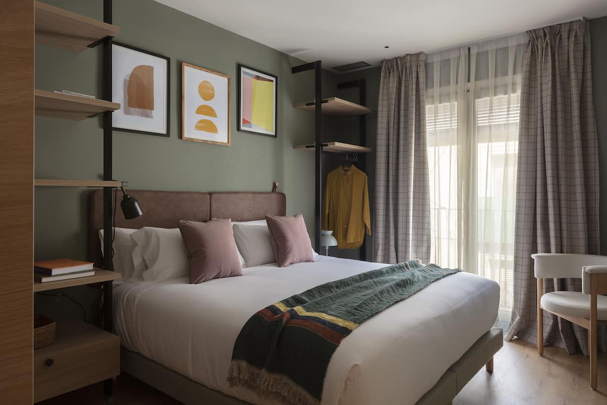 A modern bedroom with a bed, bedside tables, a wardrobe, and artwork on the wall.