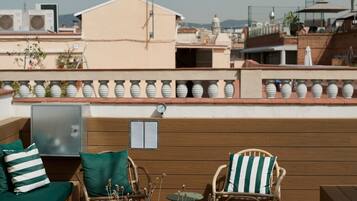 A rooftop terrace with outdoor seating, a clock, and a view of the cityscape.