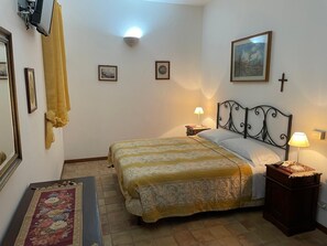 A bedroom with a bed, bedside lamps, a cross on the wall, and framed pictures. - Villa Luca (Sant'Agata di Militello)