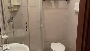 A bathroom with a glass-enclosed shower, a white sink, a toilet, and a bidet.