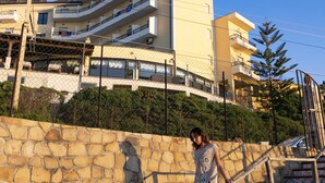 A person descending a stone staircase with a tiled wall and a building in the background. - Hotel Za' Maria (Caronia)