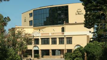 A two-story building with a large glass facade, a balcony, and a sign reading "Hotel Za'Maria".