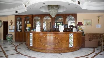 A reception area with a marble floor, a central reception desk, and a chandelier.
