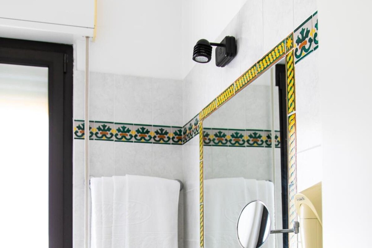 A bathroom with a sink, mirror, towel rack, and a window.