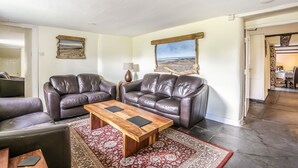 Ein Wohnzimmer mit zwei Ledersofas, einem Holztisch und einem roten Teppich mit Muster.