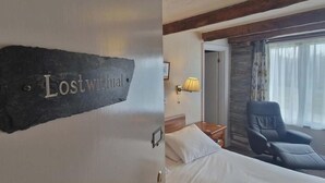 Ein Hotelzimmer mit einem Bett, einem Sessel, einer Lampe und einem Schild mit der Aufschrift 'Lostwithal'.