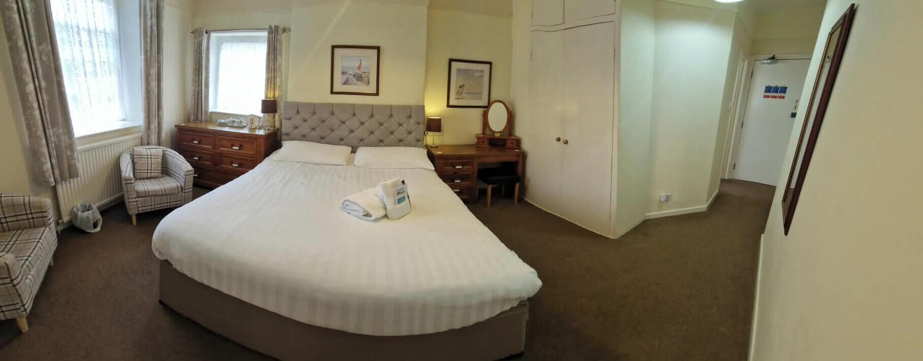 Una habitación de hotel con una cama grande, una silla, un escritorio y un armario.