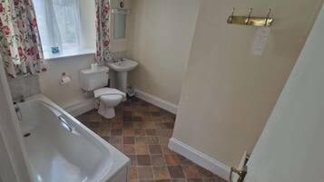 Un baño con bañera, inodoro y lavamanos.