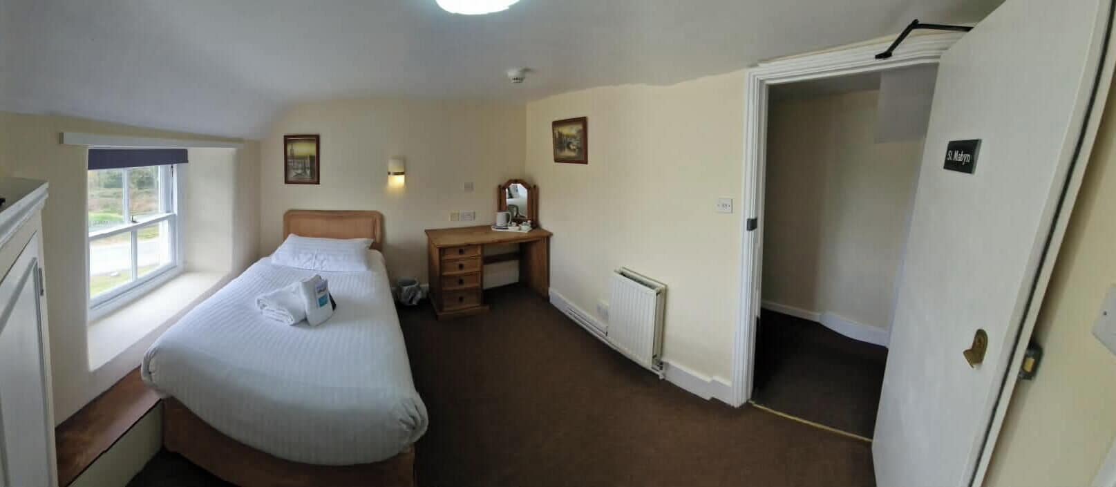 Une chambre avec un lit, un bureau, un radiateur et une fenêtre.