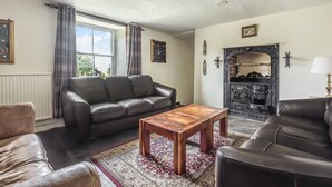 Ein Wohnzimmer mit einem braunen Ledersofa, einem Holztisch und einem gemusterten Teppich.