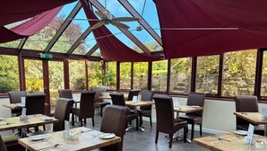 Ein Restaurant mit Glasdecke, Holztischen und -stühlen.