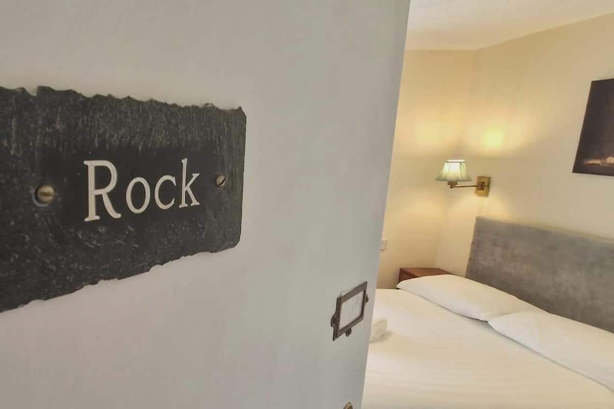 A room with a bed, a wall-mounted light, and a sign that reads 'Rock'.