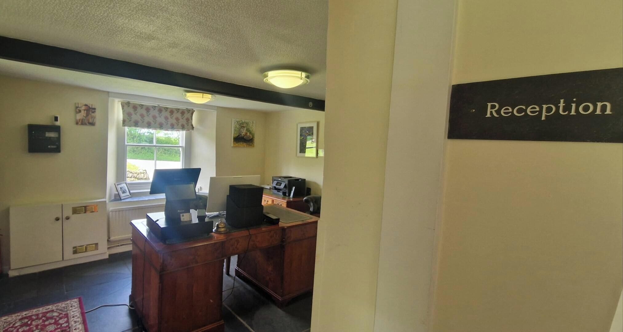 A reception area with a desk, computer, and a sign labeled 'Reception'.