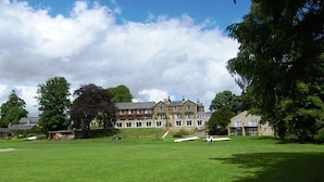 A large, open grassy field with a historic building in the background. - Riverdale Hall Hotel (Hexham)