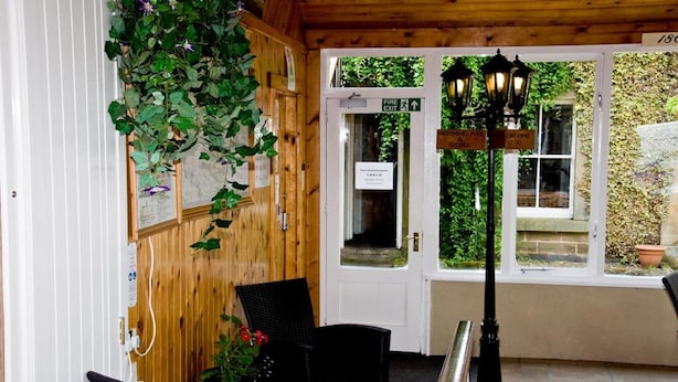 A wooden interior with a white door marked "Fire Exit," black wicker chairs, and a potted plant. - Riverdale Hall Hotel (Hexham)