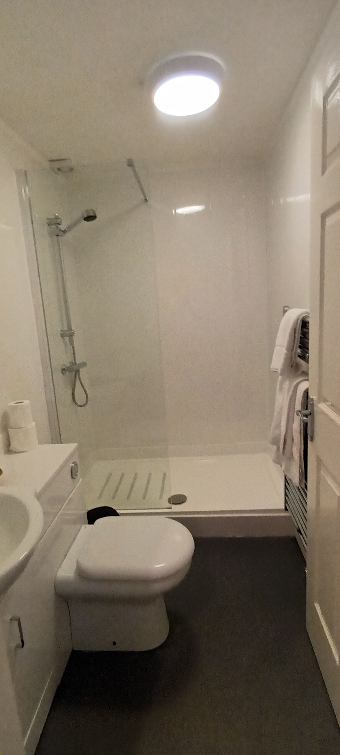 Et lille badeværelse med toilet, håndvask og brusebad.