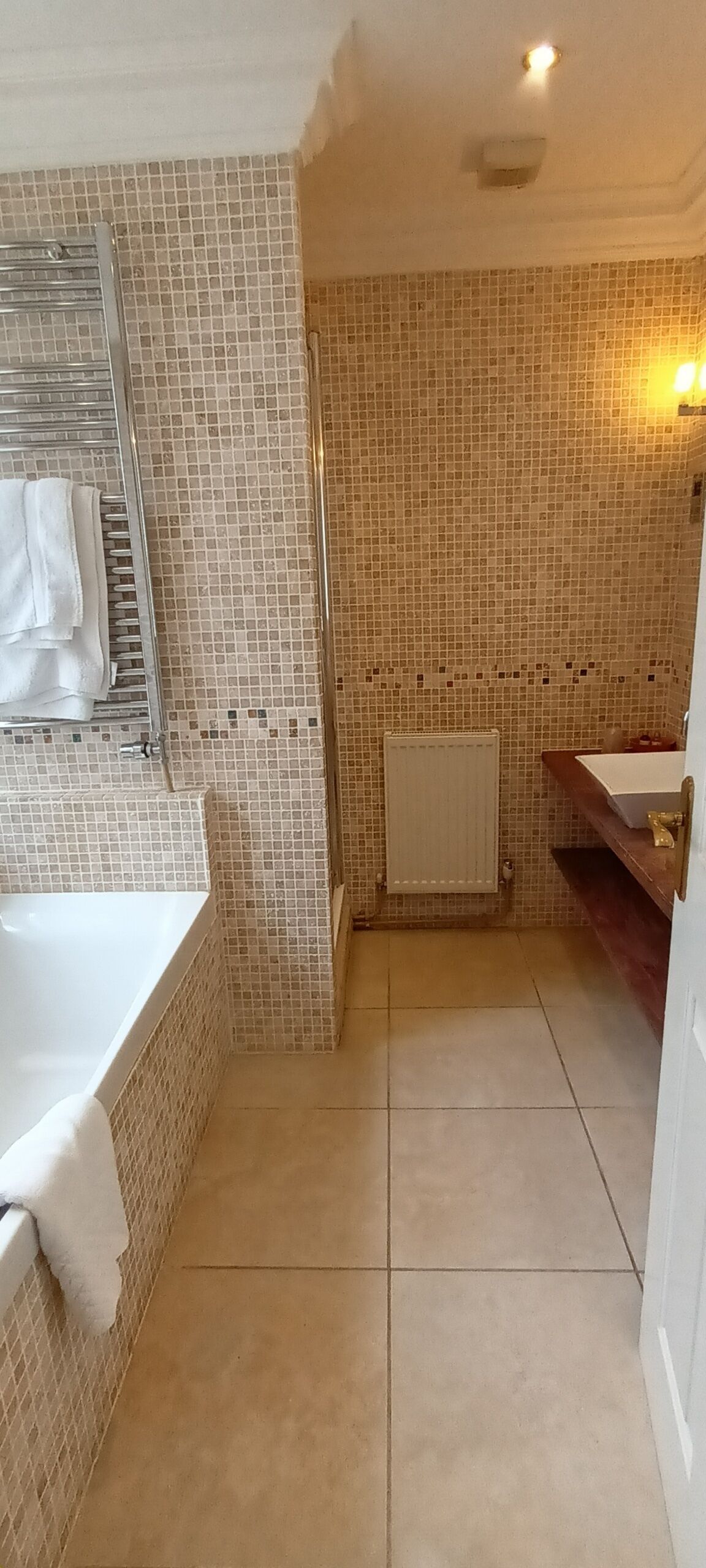 Ein Badezimmer mit Badewanne, Dusche, Waschbecken und gefliesten Wänden.