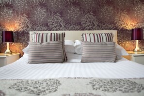 A neatly made bed with striped pillows and a floral-patterned headboard. - Trelawney Hotel (Torquay)