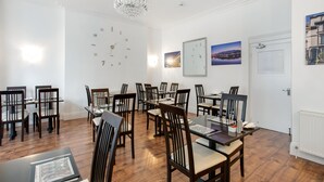 A dining area with wooden tables and chairs, a chandelier, and artwork on the walls.