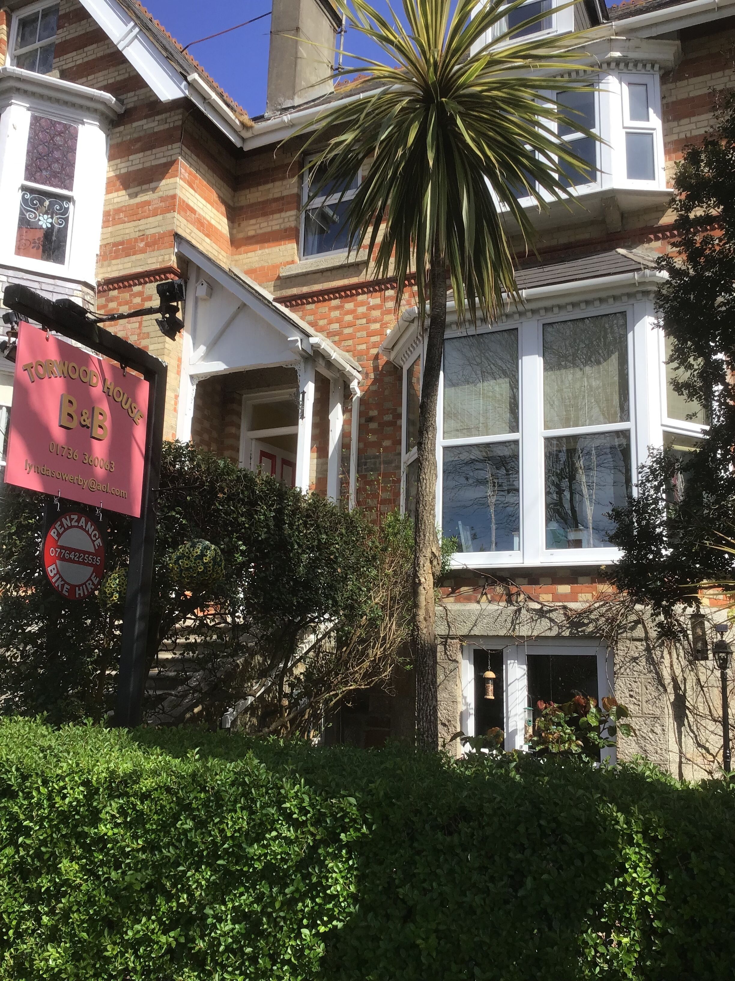 A traditional brick house with a large bay window and a prominent red sign for 'Torwood House B&B'.
