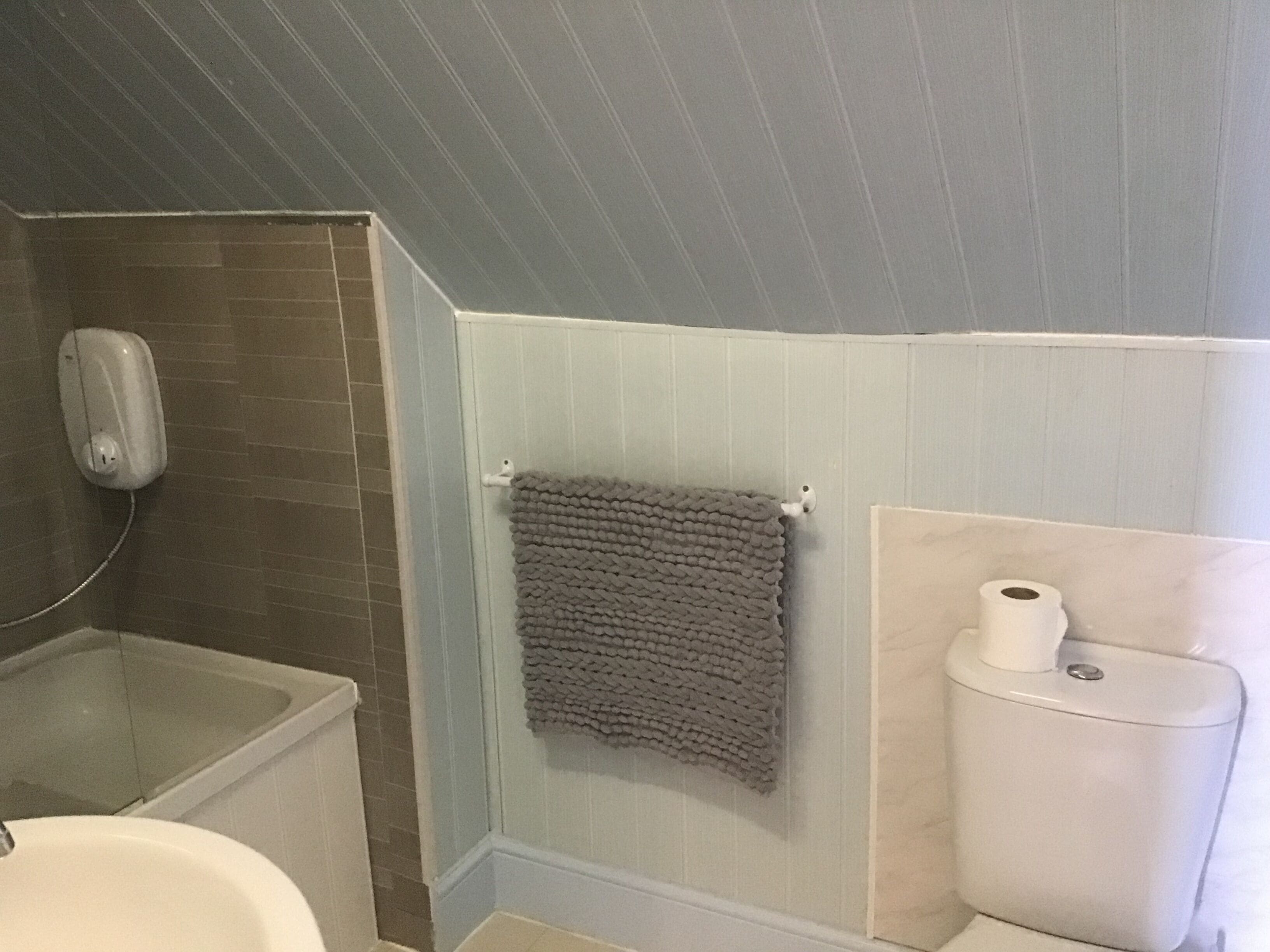 A bathroom with a bathtub, a toilet, and a towel rack.