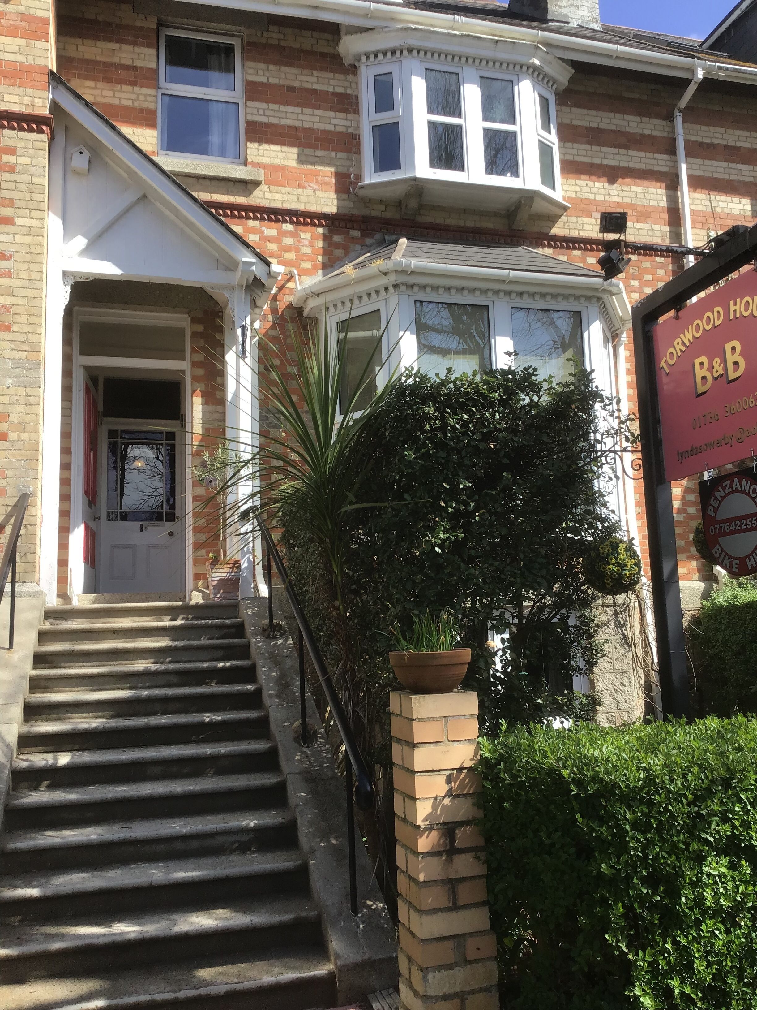 A two-story building with a front entrance, a staircase, and a sign for Torwood House B&B.