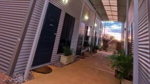 A modern building with a covered walkway and a large window. - Mia Mia House in the Desert (Newman)