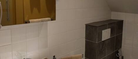 A bathroom with a white sink, a mirror, a toilet, and a towel rack.
