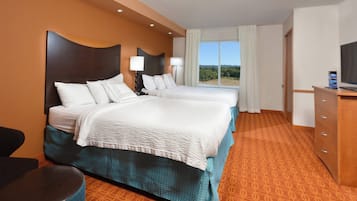 A hotel room with two beds, a TV, a desk, and a view of the outdoors.
