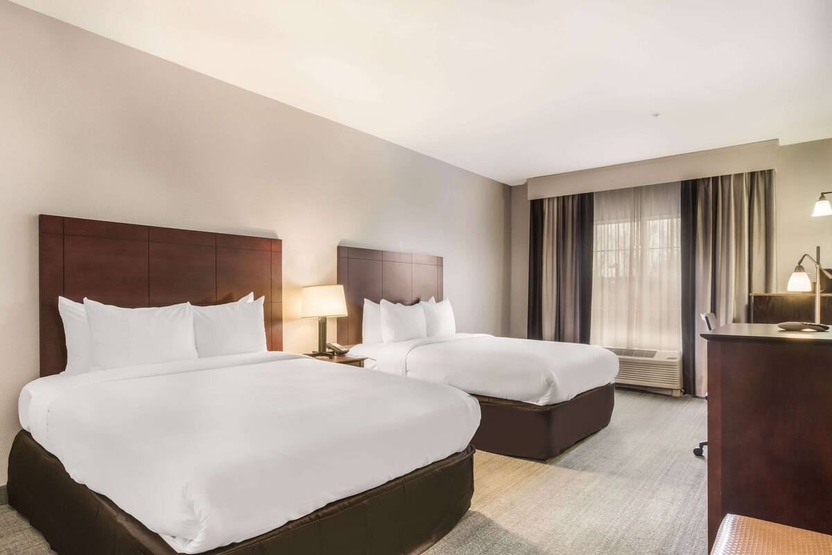 Une chambre d’hôtel avec deux lits, un bureau et une chaise.