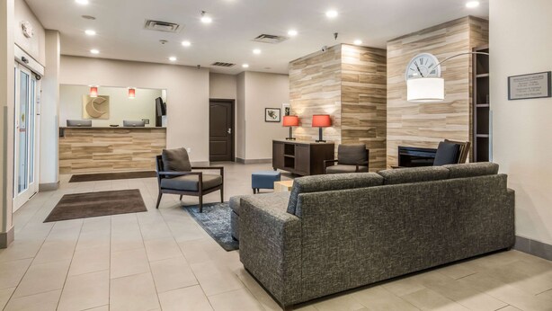 Un hall d’hôtel moderne avec un comptoir d’accueil, un espace salon et une horloge au mur.