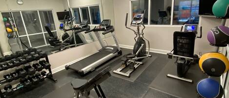 A gym with treadmills, elliptical machines, and weightlifting equipment.