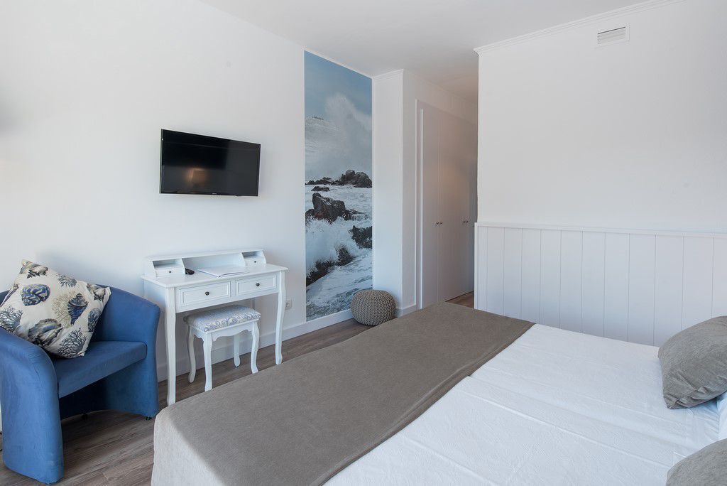 Een slaapkamer met een bed, een bureau, een stoel en een televisie die aan de muur is bevestigd.