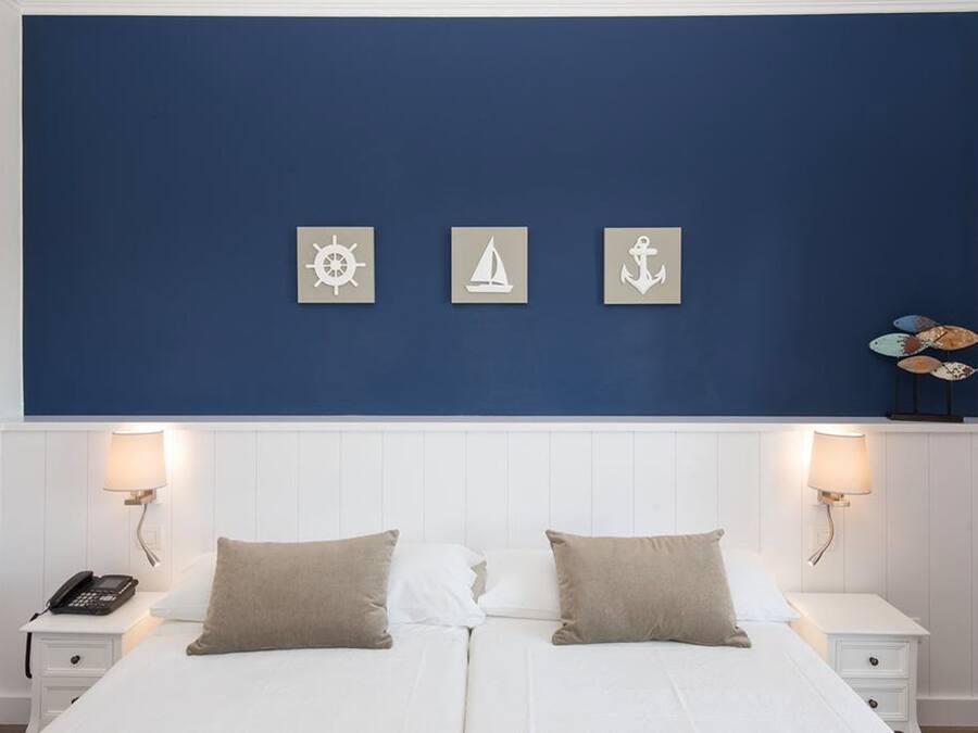 A double bed with two bedside tables, each with a lamp and a phone.