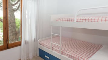 A bunk bed with a white frame and red and white checkered bedding.