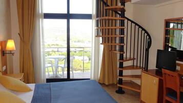 Une chambre d’hôtel avec un lit, un bureau équipé d’un ordinateur, une télévision, un escalier en colimaçon et un balcon avec vue.