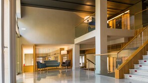 A spacious lobby with a modern staircase, a seating area with a sofa and chairs, and a large window providing natural light. - Golden Acqua Salou (Salou)