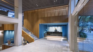 A spacious lobby with a wooden reception desk, a staircase, and a glass wall reflecting the outside. - Golden Acqua Salou (Salou)