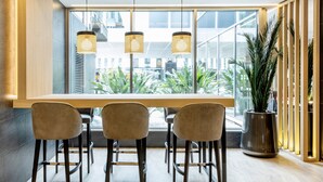 Un comedor moderno con una mesa larga, tres sillas y lámparas colgantes.