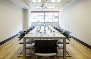 A conference room with a long table, chairs, and a projector on the ceiling.